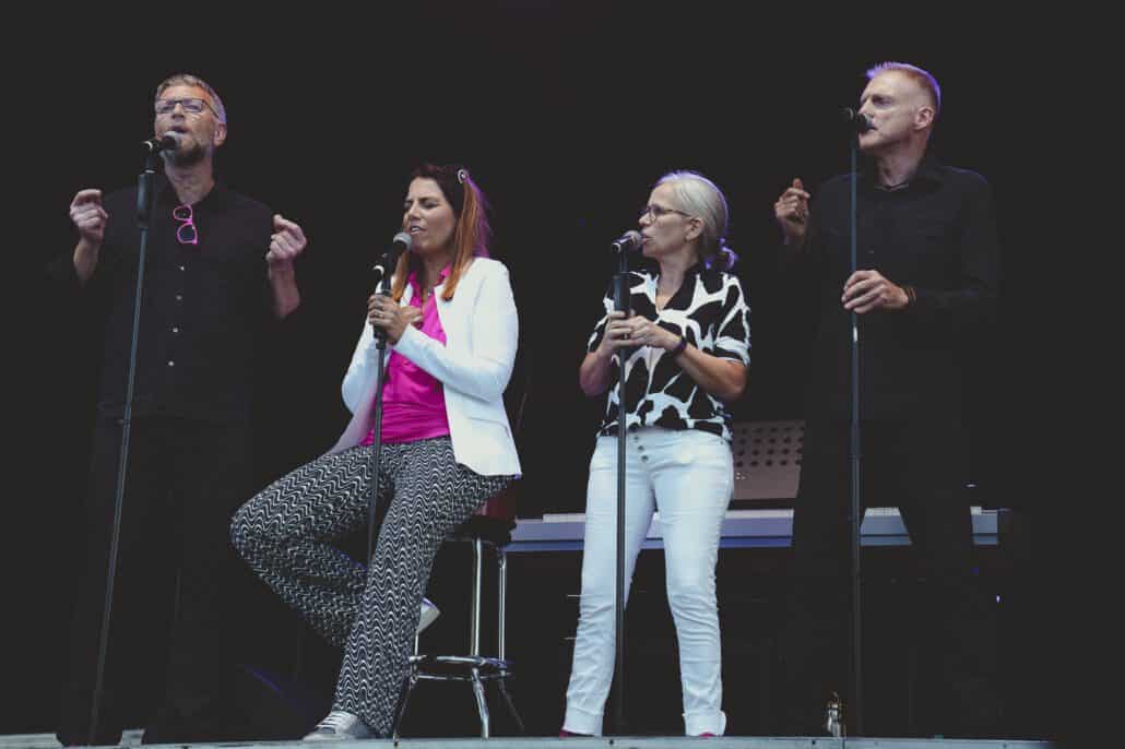 Vier Personen singen auf einer Bühne.