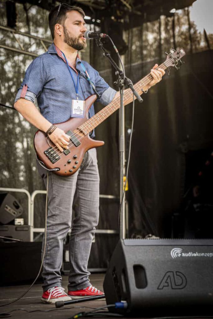 Bassist singt live auf Festivalbühne.