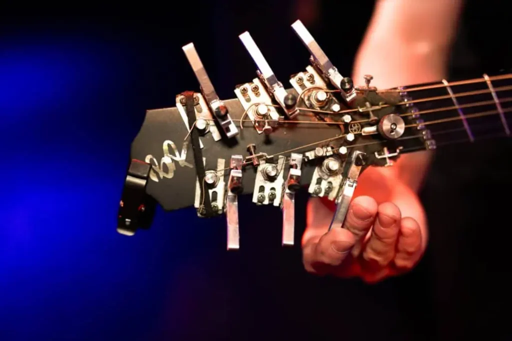 Hand hält einzigartige, mechanische Gitarre auf Bühne.