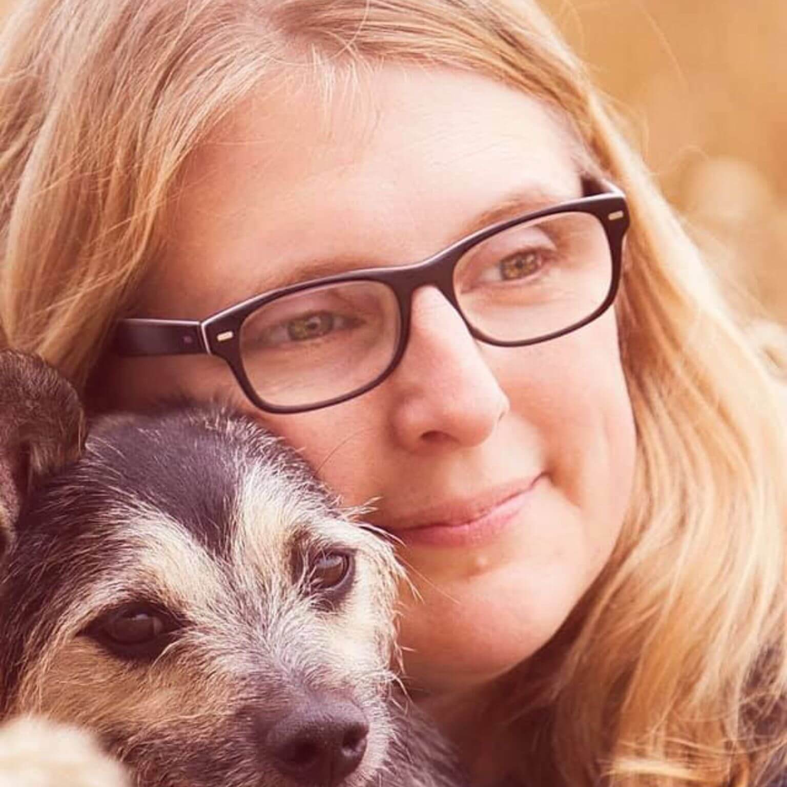 Frau mit Brille umarmt liebevoll ihren Hund.