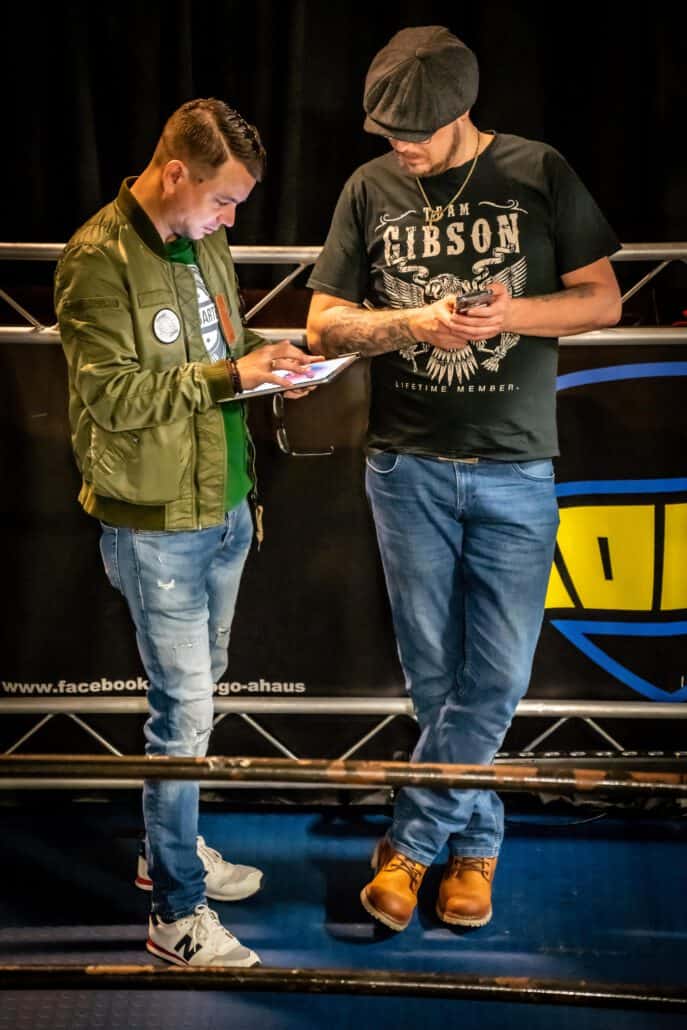 Zwei Männer überprüfen Handys im Boxring.