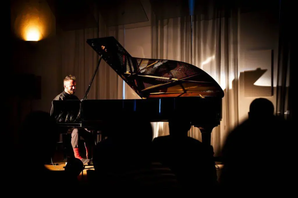 Pianist spielt auf Bühne im Scheinwerferlicht.