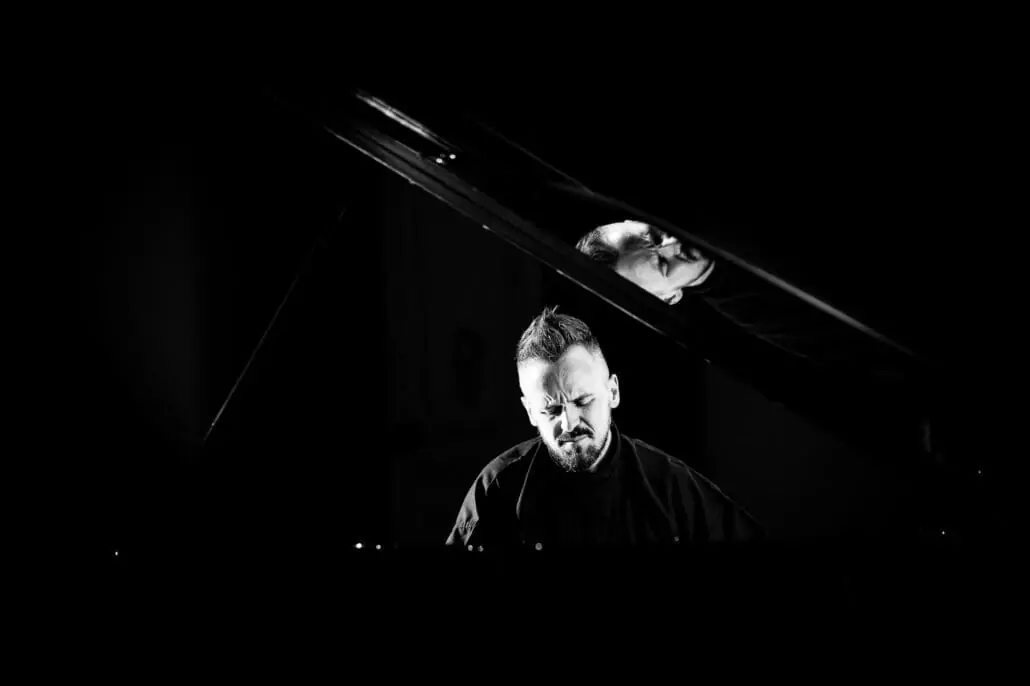 Mann spielt intensiv Klavier im Dunkeln.