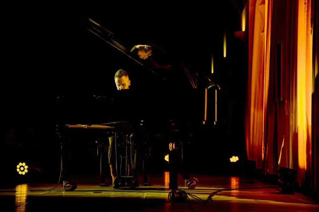 Pianist und Sängerin bei Konzert auf dunkler Bühne.