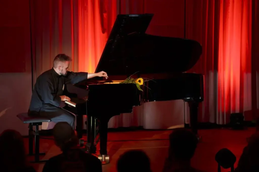 Pianist spielt bei Konzert unter rotem Licht.