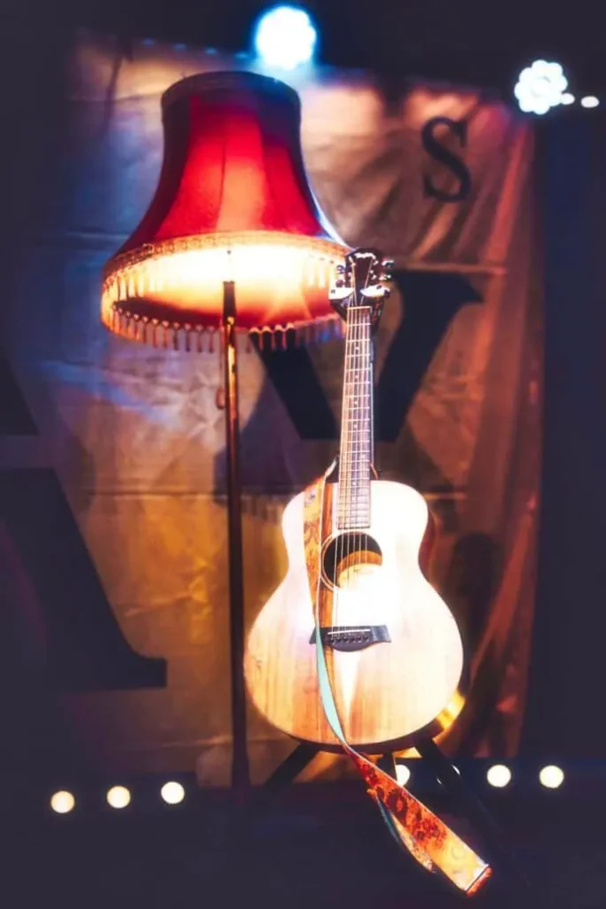 Rote Tischlampe und Gitarre auf Bühne.