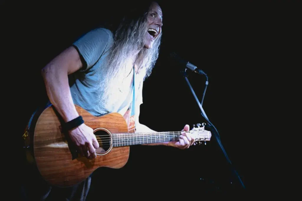 Gitarrist singt begeistert auf dunkler Bühne.