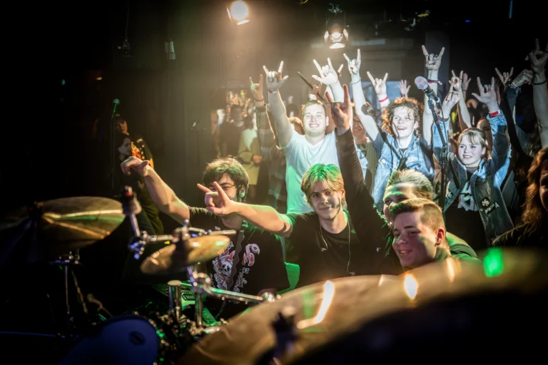Band auf Bühne mit jubelndem Publikum.