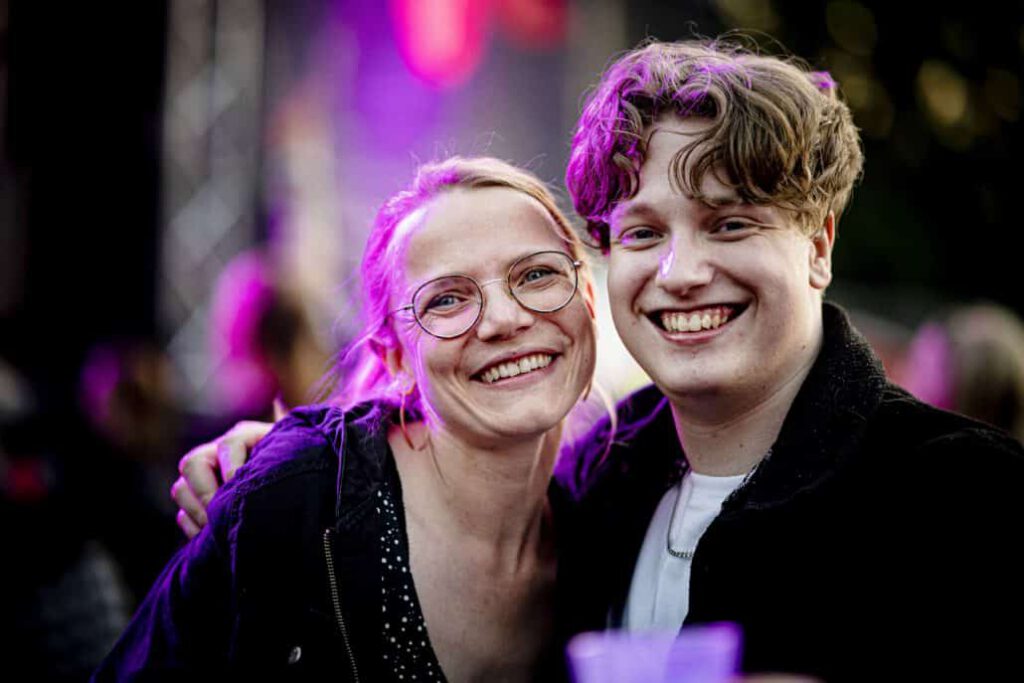 Lächelndes Paar bei einem Konzert mit lila Lichtern.