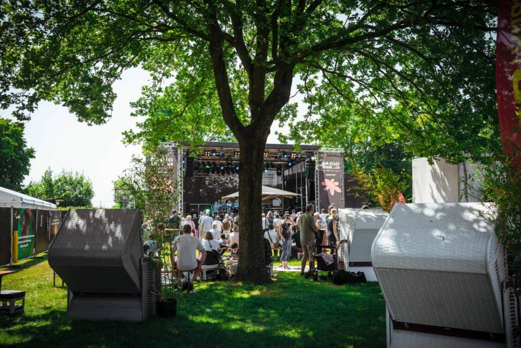 Outdoor-Festival mit Bühne und entspannten Besuchern im Park.