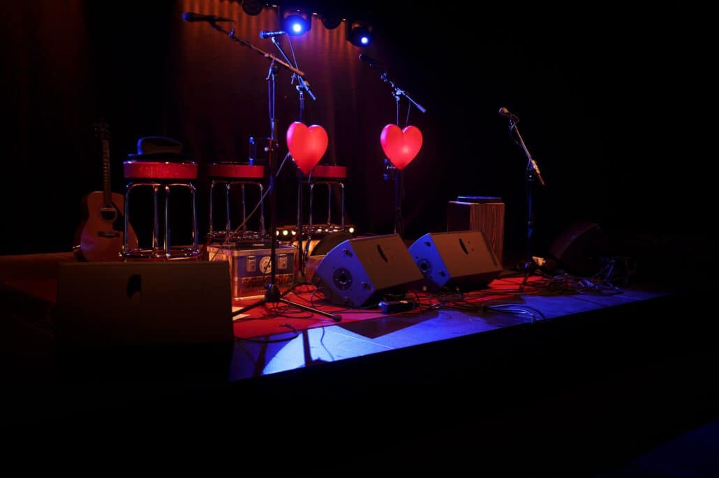 Bühne mit Instrumenten und herzförmigen Ballons bei Nacht.