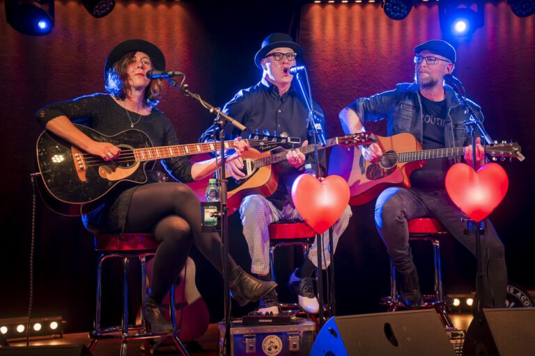 Drei Musiker spielen Gitarre auf der Bühne.
