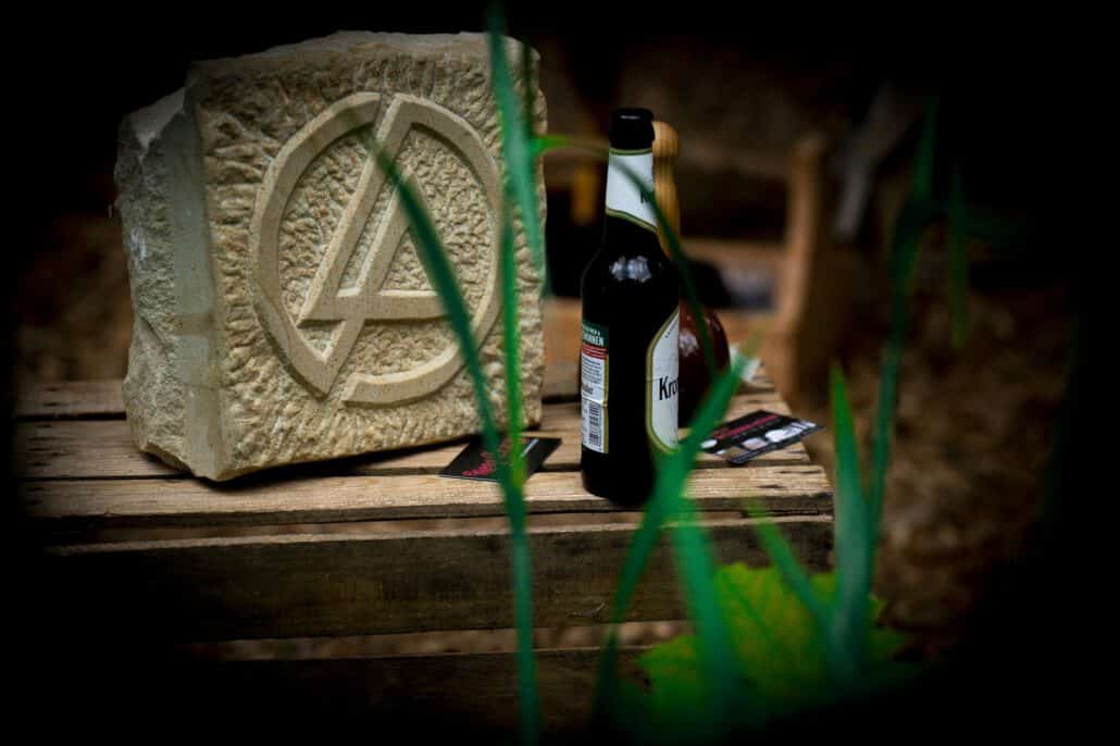 Steinschnitzerei und Bierflasche auf Holzbrett.