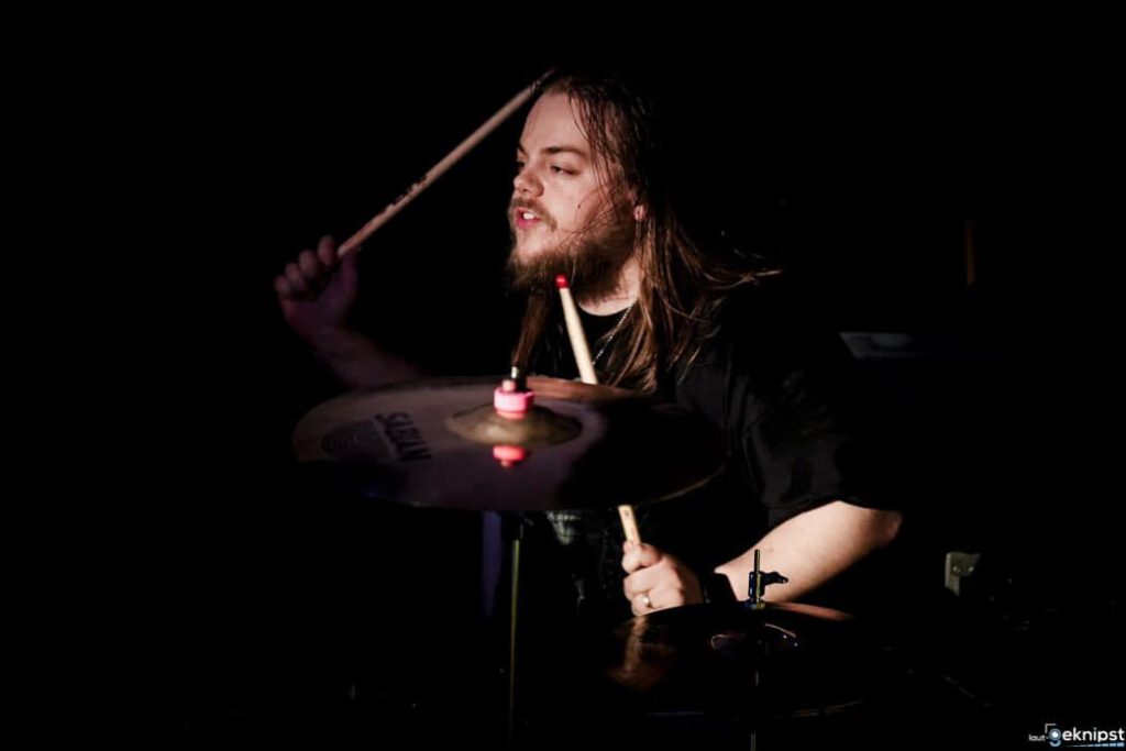 Schlagzeuger spielt intensiv im Dunkeln.