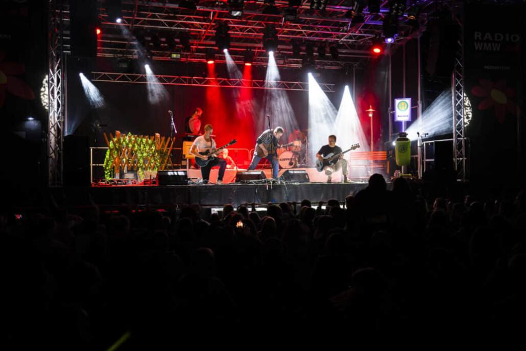 Band spielt auf beleuchteter Bühne vor Publikum.
