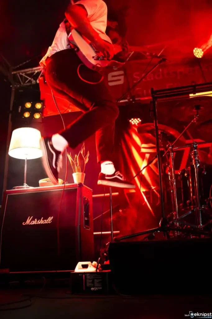 Gitarrist springt während Konzert auf der Bühne.