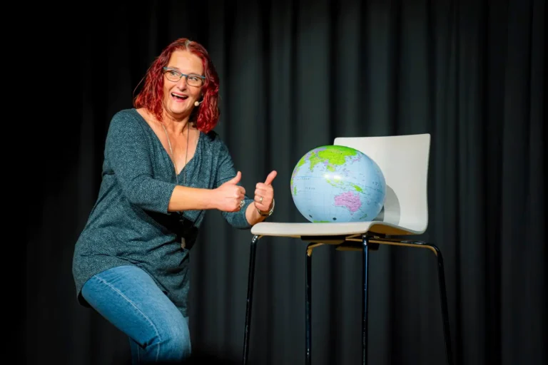 Frau mit Globus und Laptop zeigt Daumen hoch.