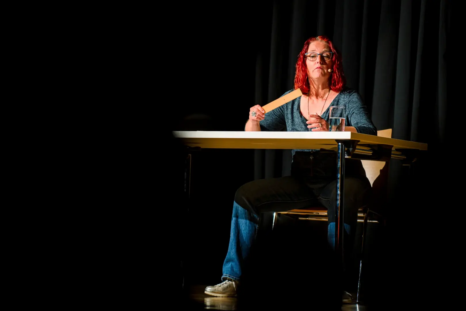 Frau mit roten Haaren hält Holzlöffel auf Bühne.