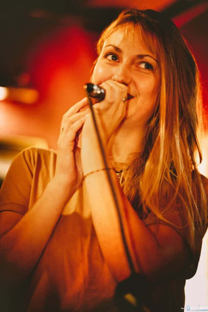 Sängerin lächelt beim Mikrofongesang auf Bühne.