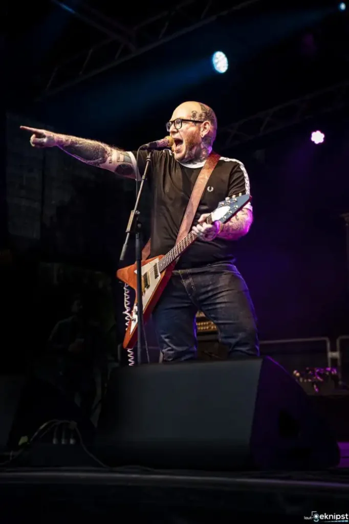 Sänger mit Gitarre auf Rock-Konzertbühne.