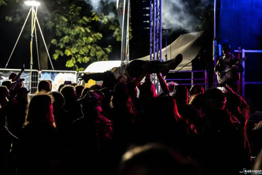 Crowdsurfing bei Nacht auf einem Musikfestival.