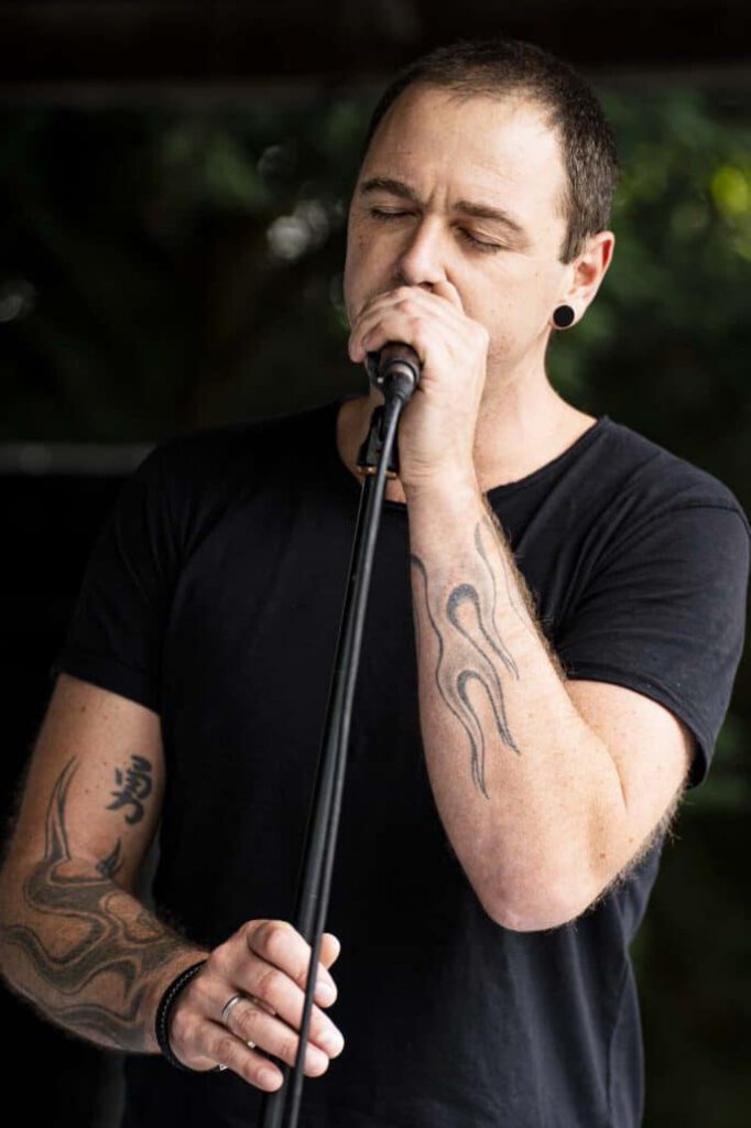 Sänger mit Mikrofon und sichtbaren Tattoos.