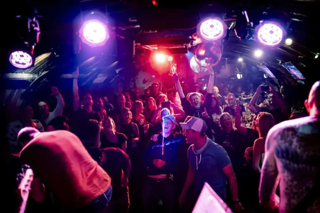 Leute tanzen in beleuchtetem Nachtclub.