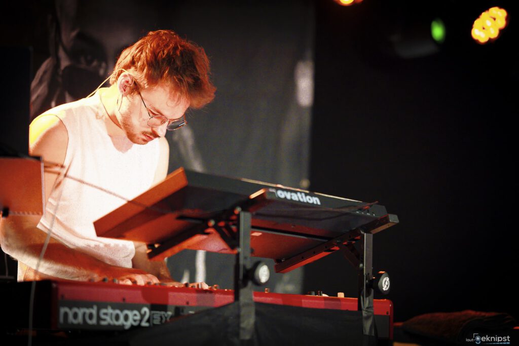 Musiker spielt intensiv auf rotem Keyboard.