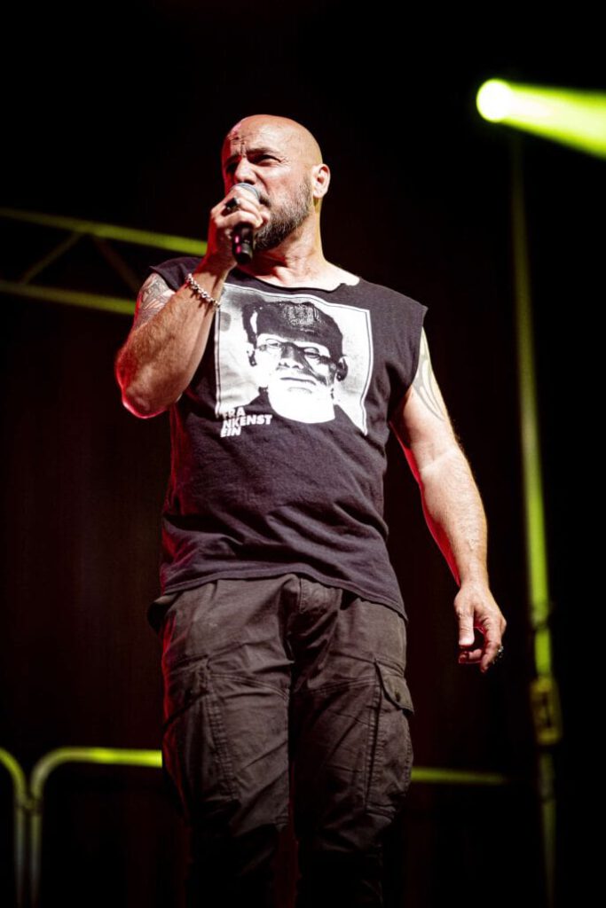 Sänger auf Bühne mit Mikrofon und bedrucktem T-Shirt.