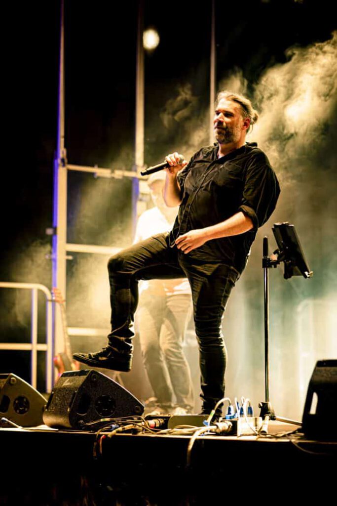 Sänger performt leidenschaftlich auf Bühne mit Nebel.