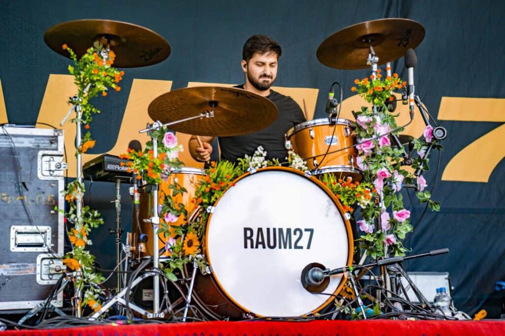 Schlagzeuger mit Blumendekor auf der Bühne.