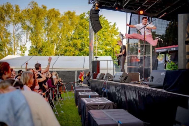 Sänger springt auf Bühne bei Open-Air-Konzert.