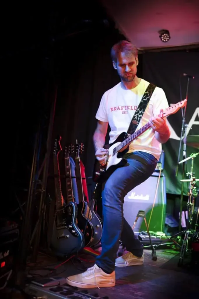 Gitarrist spielt auf Bühne mit E-Gitarre.