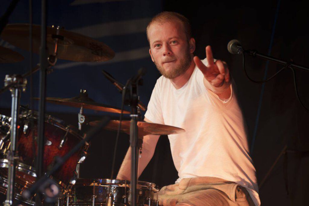 Schlagzeuger zeigt Victory-Zeichen während Konzerts.