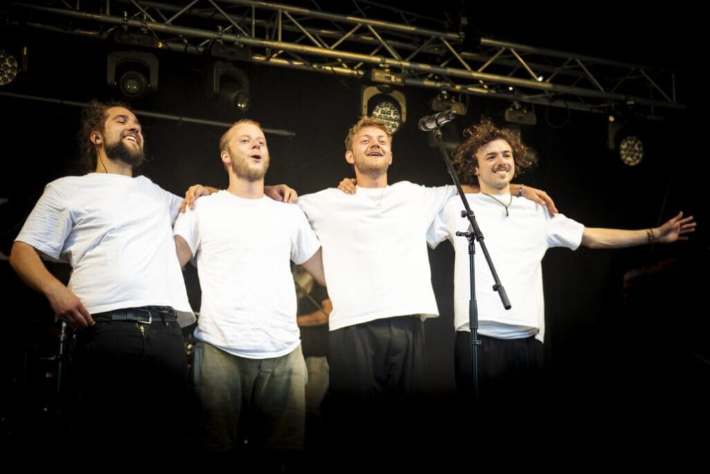 Vier Sänger umarmen sich auf der Bühne.