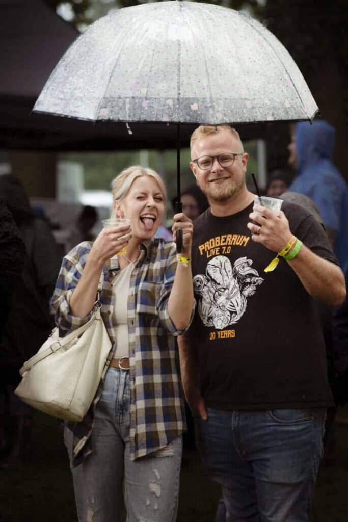 Fröhliches Paar mit Regenschirm bei Regenwetter.