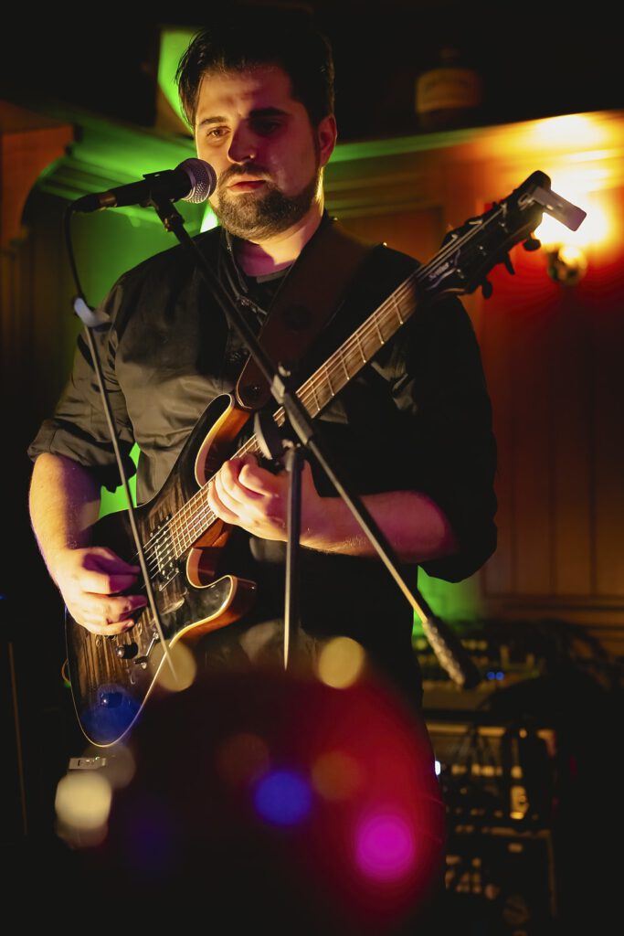 Gitarrist singt auf einer Bühne bei Nacht.