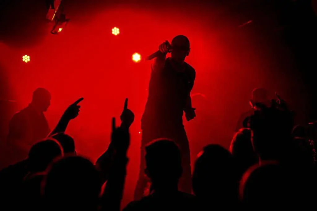 Sänger auf Bühne bei rotem Konzertlicht.
