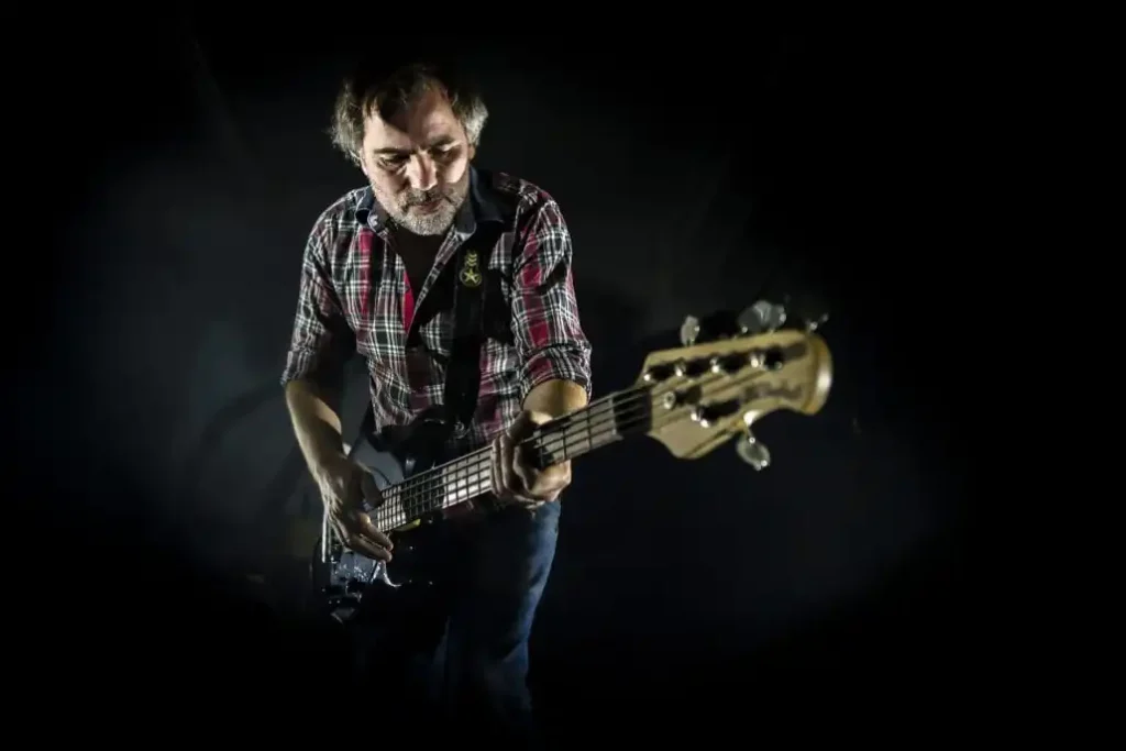 Bassist spielt konzentriert im dunklen Hintergrund.