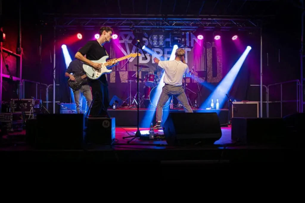 Band spielt Live-Musik auf Bühne mit bunten Lichtern.