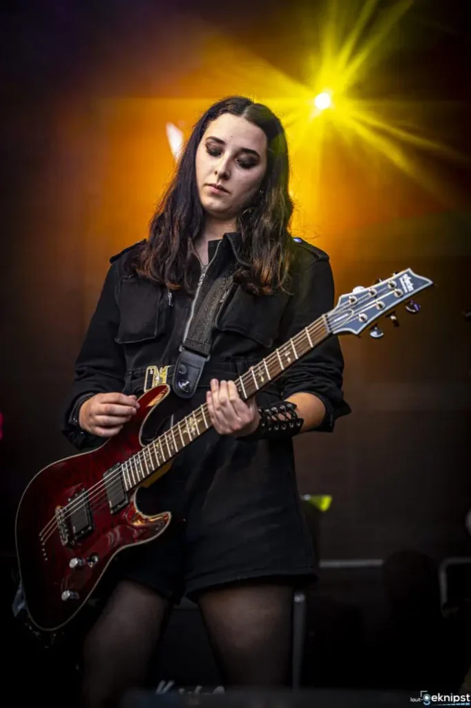 Gitarristin spielt live auf Bühne mit Lichteffekt.