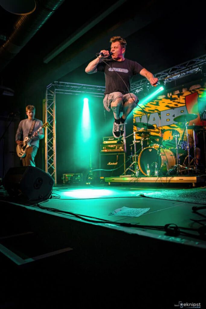 Sänger springt auf Bühne bei einem Rockkonzert.