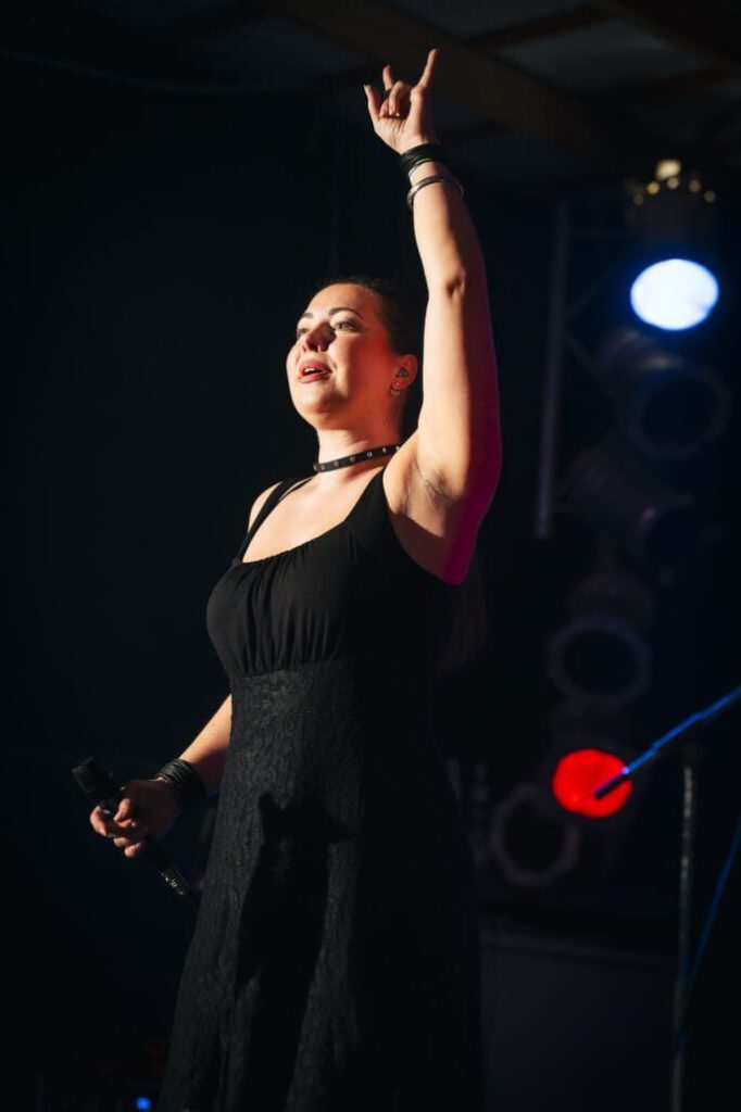 Sängerin hebt Arm auf Bühne empor.