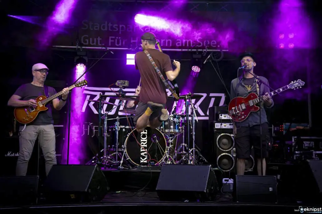 Band auf Bühne mit violettem Lichteffekt.