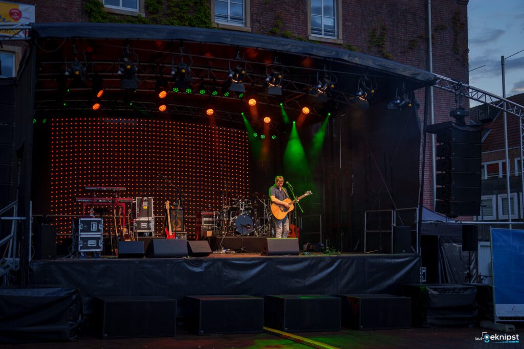 Mann spielt Gitarre auf bunter Bühne