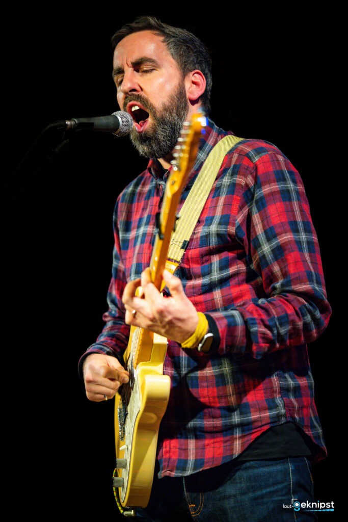 Mann singt und spielt Gitarre auf der Bühne