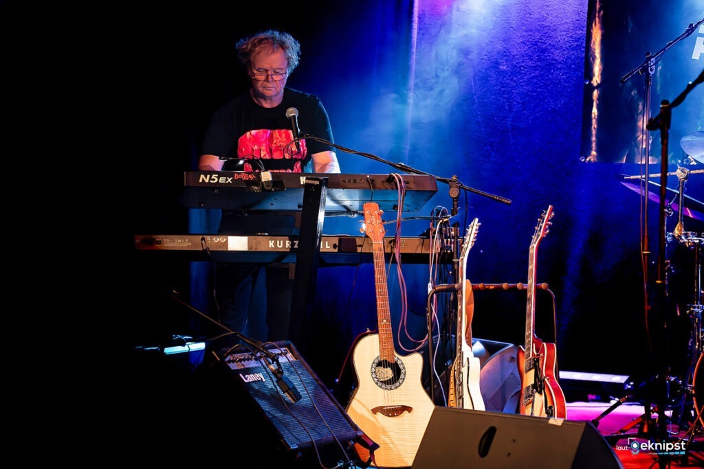 Musiker spielt Keyboard auf Bühne mit Gitarren