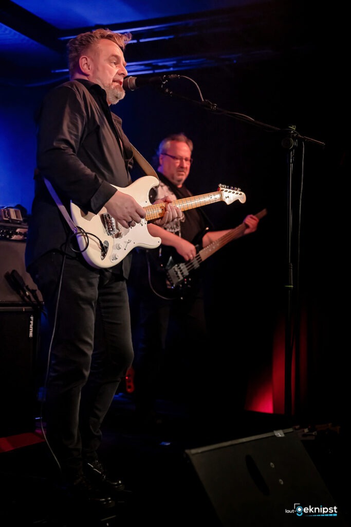 Musiker spielen live auf der Bühne mit Gitarren.