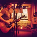 Musiker spielt Gitarre und singt im Café.