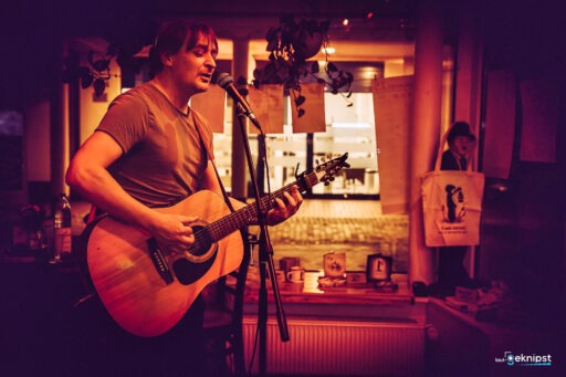 Musiker spielt Gitarre und singt im Café.